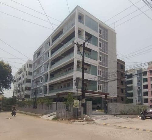 Corner-View Residency apartment building with glass balcony railings behind a gated, landscaped compound