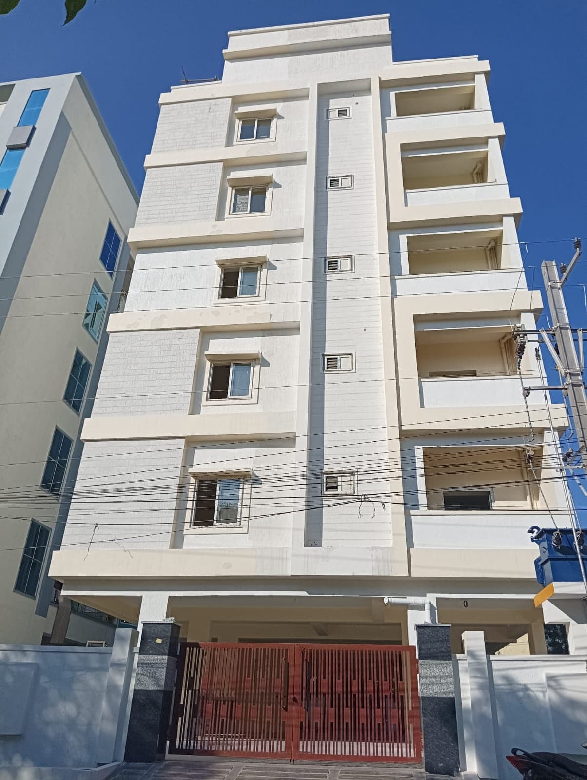 Cream Facade Residency apartment building with a central decorative vertical fin and a maroon metal entrance gate