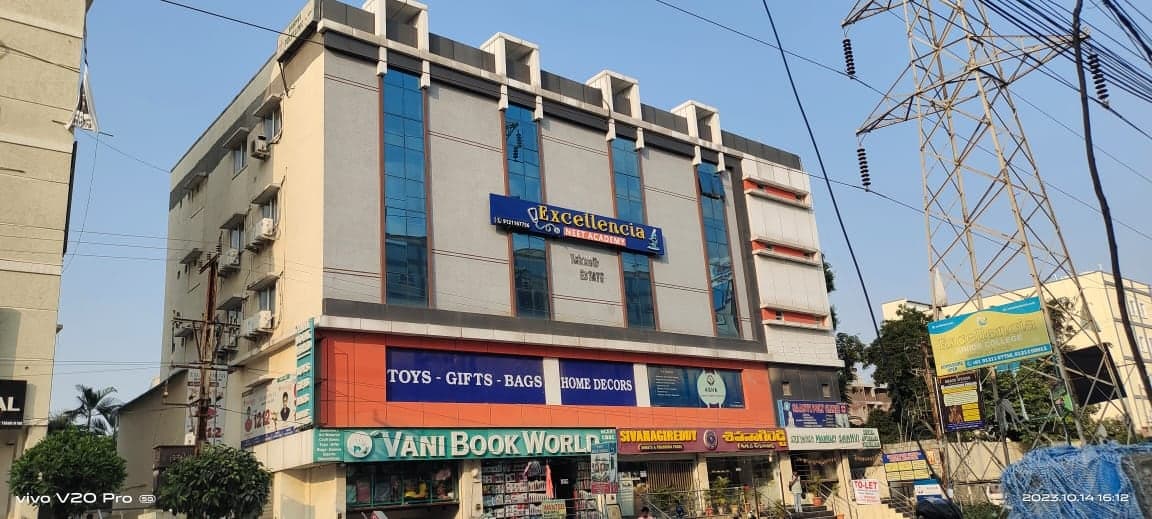 Excellencia NEET Academy building with glazed facade and ground-floor retail frontage