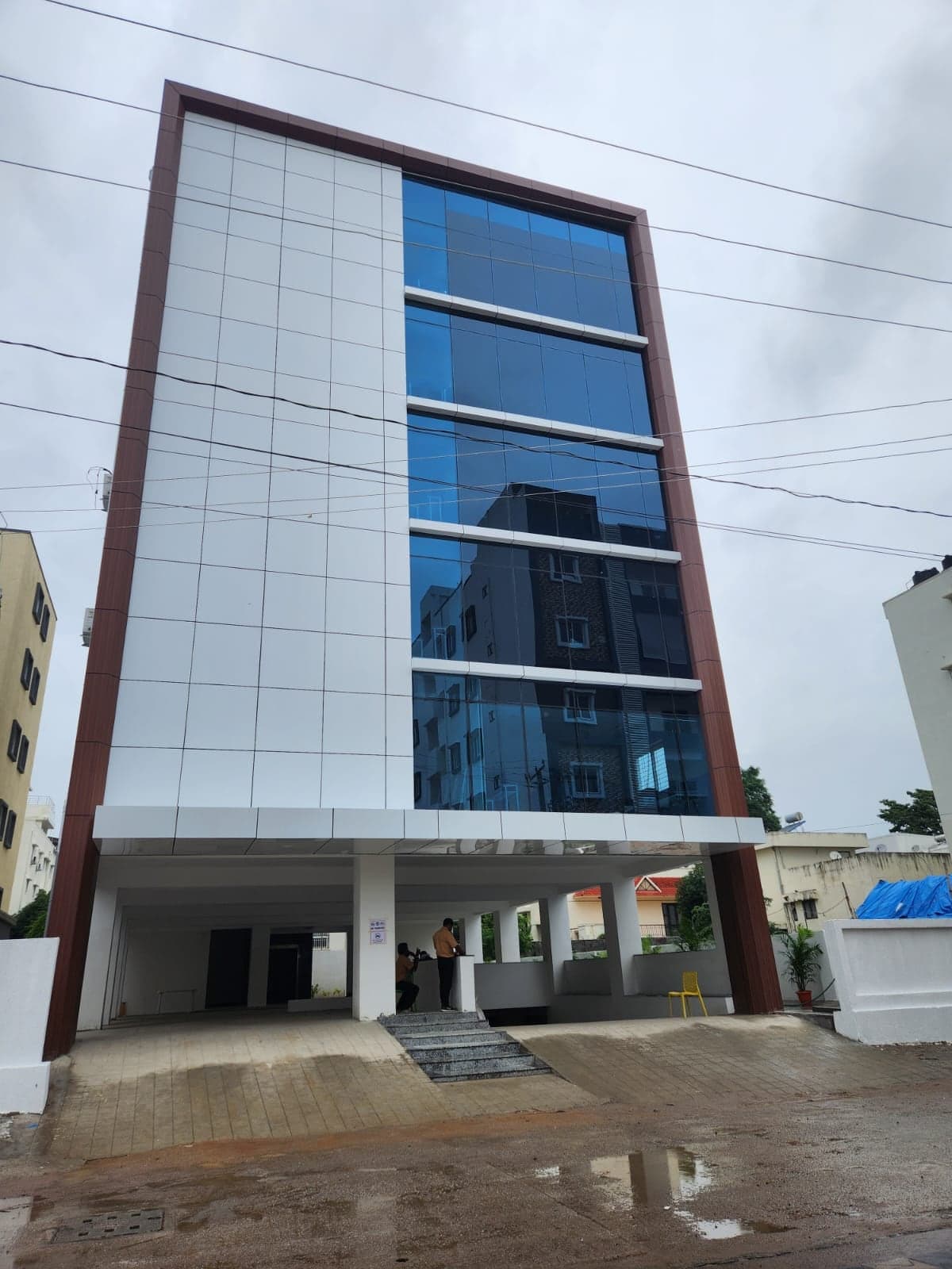 Commercial building with maroon frame edges, blue glass curtain wall and white panel cladding over covered ground-floor parking